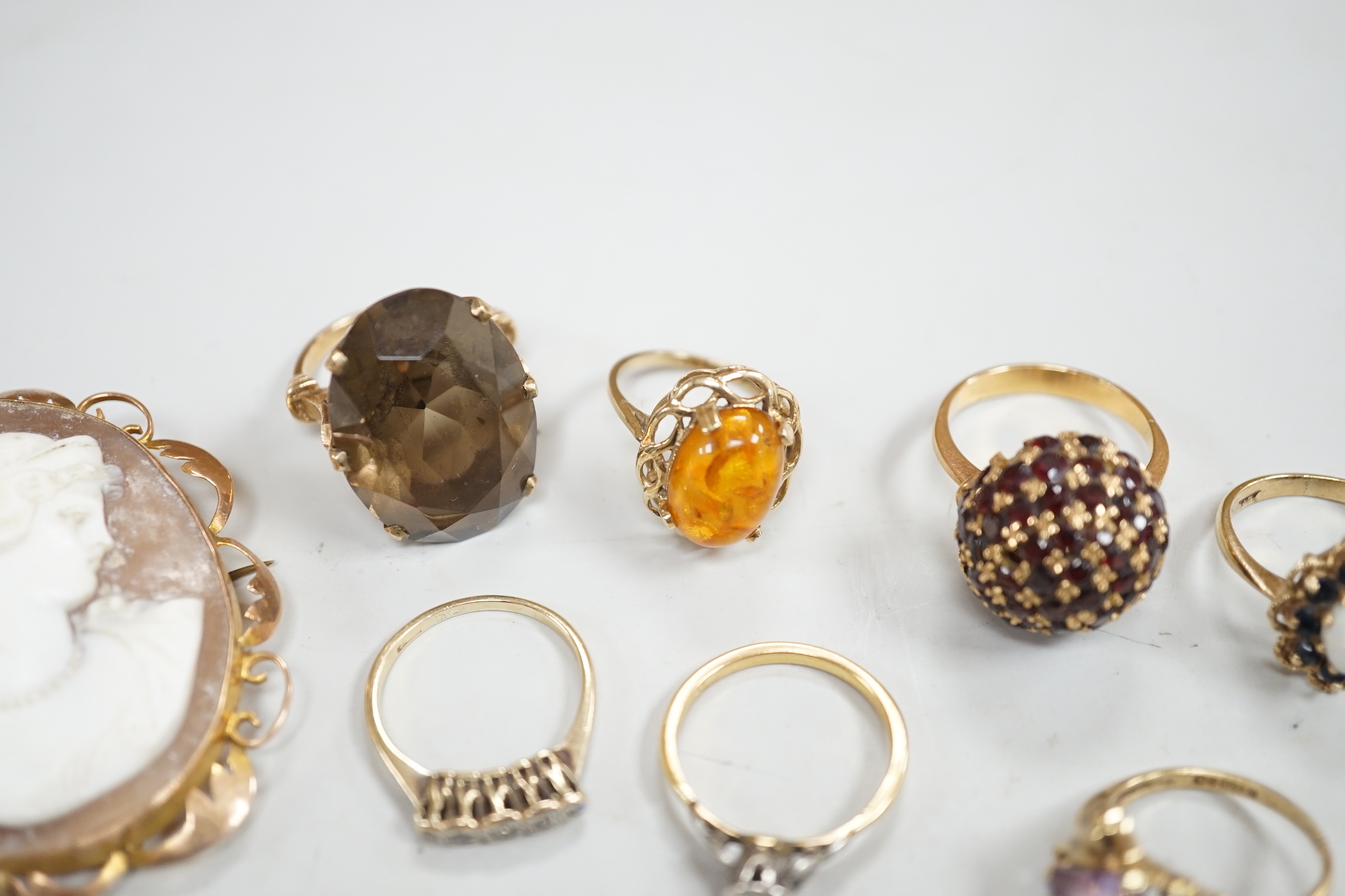 Two yellow metal and illusion set diamond rings, two 9ct gold and gem set rings, two yellow metal and gem set rings and two brooches, including 9ct mounted cameo shell.